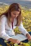 girl reading Bible in yellow flowers